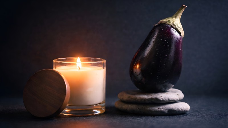 Candlelight and glossy eggplant still life
